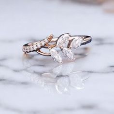 a close up of a ring on a marble surface with the reflection of it's leaves