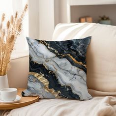 a marble pillow sitting on top of a couch next to a cup