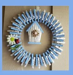 a blue and white birdhouse shaped wreath with flowers on the front, attached to a wall