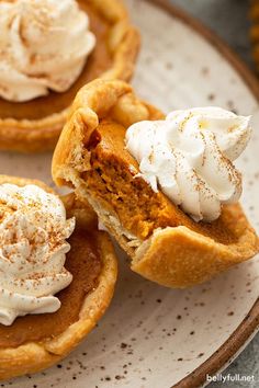 three mini pumpkin pies with whipped cream on top are sitting on a white plate