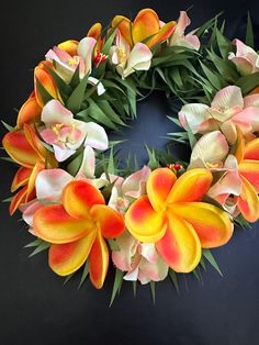 an orange and yellow flower wreath on a black background with greenery in the center