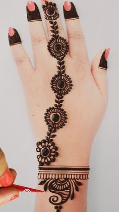 hendi design on the palm of a woman's hand with black and pink nail polish