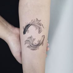 a woman with a tattoo on her arm has a fish in the shape of a circle