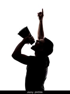 a man raising his hand up in the air while holding a black cup - stock photo