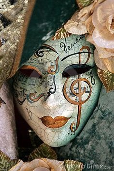 a mask with music notes painted on it and flowers in front of it, as well as roses