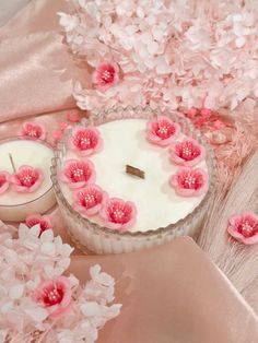 pink flowers and candles are on the table next to each other, with one candle in the middle