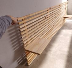 a person is holding onto a wooden slatted bench that has been built into the wall