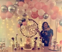 a woman standing in front of a cake surrounded by balloons