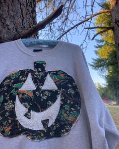 a t - shirt with an image of a pumpkin on it hanging from a tree