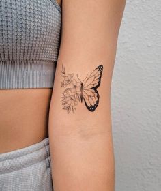 a woman's arm with a butterfly and flower tattoo on the left side of her arm