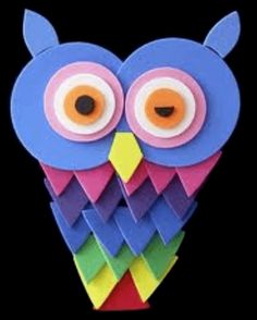 an owl made out of colored paper on a black background