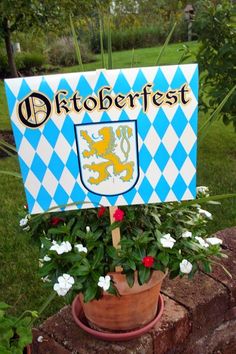 a blue and white sign sitting on the side of a brick wall next to flowers