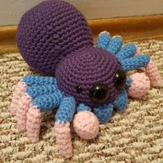 a crocheted purple and blue stuffed animal laying on the floor next to a wall