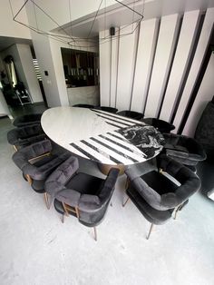 a large table with chairs around it in the middle of a living room filled with black and white furniture