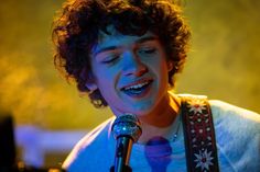 a young man singing into a microphone while holding a guitar in front of his face