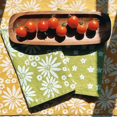 tomatoes in a wooden tray on a floral tablecloth with place mats and napkins