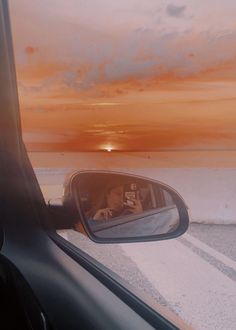 a woman is seen in the side view mirror of a car as the sun sets