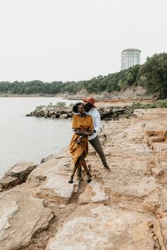 two people standing on rocks near the water