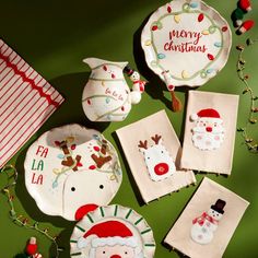 christmas themed dishes and napkins are arranged on a green surface