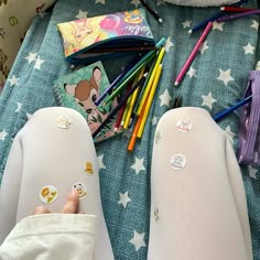 a child's feet with pencils and markers on the bed next to them