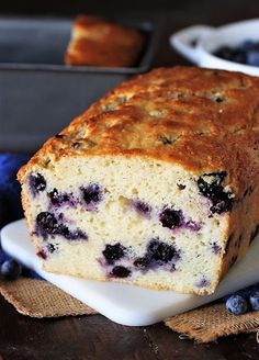 a loaf of blueberry bread sitting on top of a white plate next to some blueberries