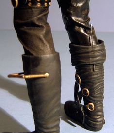 a close up of a person's legs wearing black leather boots with gold buckles