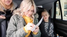 a woman holding a pair of scissors while sitting in a car with another woman behind her