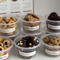 a table topped with plastic containers filled with cookies and doughnuts next to a calendar