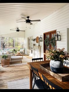 a living room filled with furniture and a wooden table next to a window on top of a hard wood floor