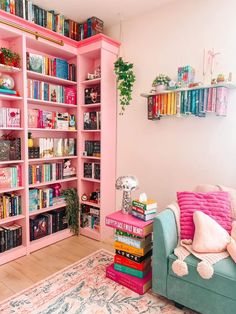 a living room filled with lots of pink bookshelves next to a blue couch