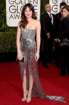 a woman in a silver and red dress on the red carpet at an awards event