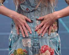 a woman with her hands on her hip wearing overalls and holding her hand behind her back