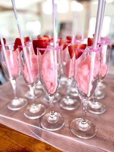 several glasses filled with ice cream and strawberries on top of a wooden table next to each other