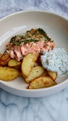 a white plate topped with potato wedges and salmon