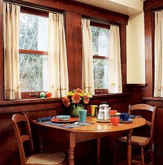 a dining room table with two chairs and a vase full of flowers on the table