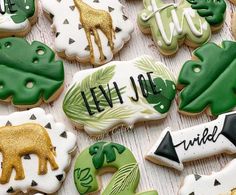 some decorated cookies are sitting on a white tablecloth with green leaves and giraffes