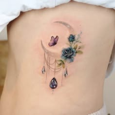 a woman's lower back tattoo with flowers and a crescent