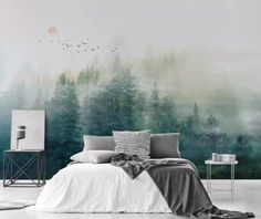 a bed with pillows and blankets in front of a forest mural on the wall behind it