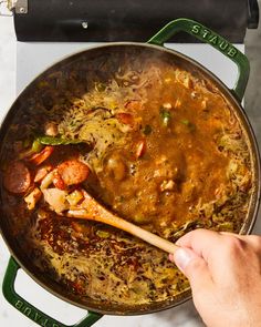 a person stirring food in a pot with a wooden spoon