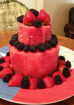 a watermelon cake with blackberries and raspberries on the top is sitting on a plate