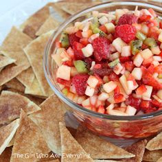 a bowl filled with fruit and chips sitting on top of a pile of tortilla chips