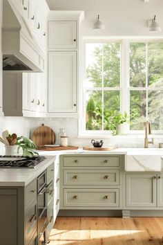 a kitchen filled with lots of white cabinets and counter top space next to a window