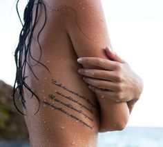 the back of a woman's body with words written on her left arm and chest