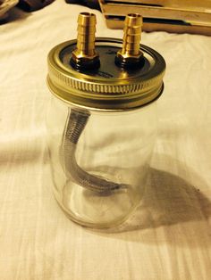 a glass jar with two brass screws in it