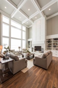 a living room filled with lots of furniture next to large windows on top of a hard wood floor