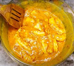 a bowl filled with yellow food and a wooden spoon