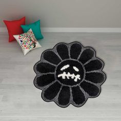 a black and white flower rug sitting on top of a wooden floor next to pillows