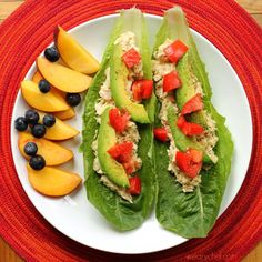 two lettuce wraps with tuna, tomatoes and blueberries on a white plate