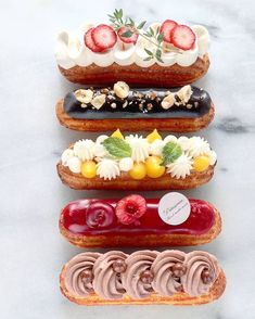 four donuts with different toppings are arranged on a marble countertop in the shape of a tower