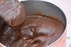 a person pouring chocolate into a metal bowl